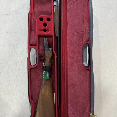 Estojo de espingarda aberto com interior em veludo vermelho e espingarda desmontada