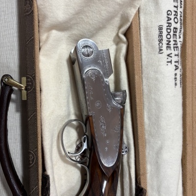 Espingarda de caça em estojo acolchoado branco com texto e estrutura em madeira e metal gravado