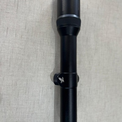 Luneta preta cilíndrica de metal sobre tecido bege