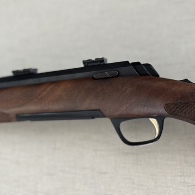 Parte de um rifle com coronha de madeira e detalhes pretos e dourados