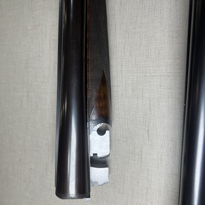 Espingarda desmantelada com canos em metal preto e punho em madeira castanha