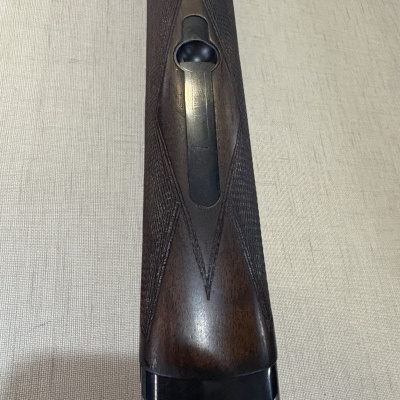 Parte de espingarda com madeira castanha e metal preto e prateado