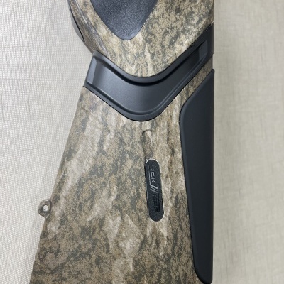 Espingarda com coronha camuflada castanho e verde, detalhes pretos e etiqueta CAL 12 GA - 28