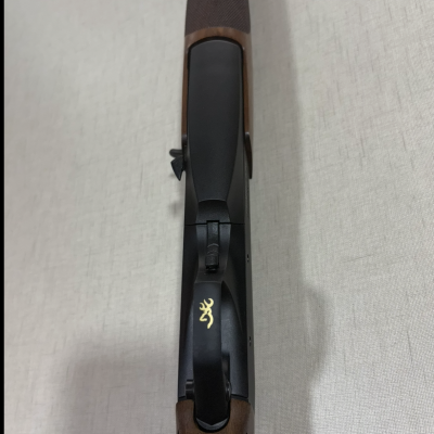 Espingarda com madeira castanha e parte superior preta com símbolo dourado