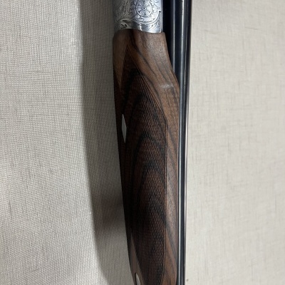 Espingarda com coronha em madeira escura e canos negros com gravuras em metal