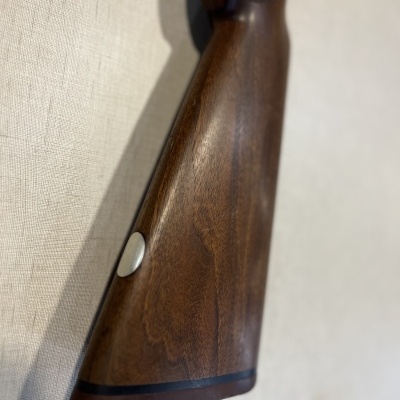 Coronha de madeira castanha lisa com botão metálico prateado em fundo branco