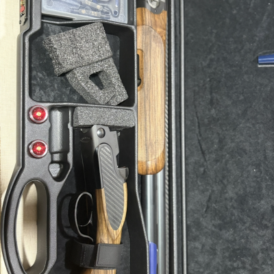 Estojo preto com arma desmontada, cápsulas vermelhas e ferramentas Beretta