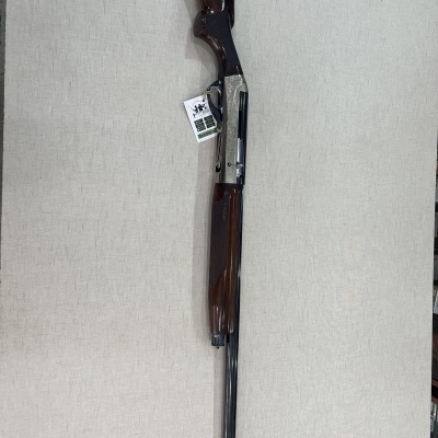 Espingarda com coronha em madeira castanha e metal prateado com etiqueta pendurada