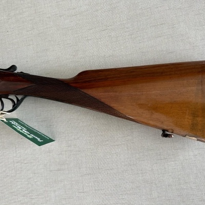 Coronha de espingarda de madeira castanha com etiqueta verde pendurada