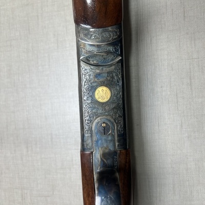 Espingarda com madeira castanha e metal gravado com medalhão dourado no centro