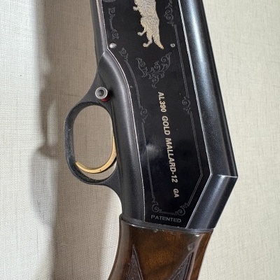 Espingarda preta com gravação de cão dourado e detalhes em madeira