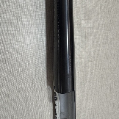 Fragmento de tubo metálico preto com papel branco rasgado num fundo cinza de tecido