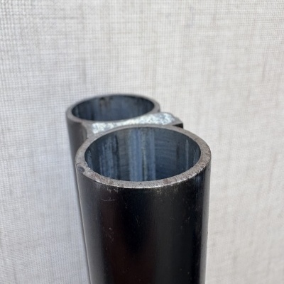 Tubo metálico preto com interior visível contra fundo claro