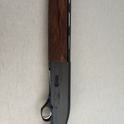 Rifle com coronha de madeira castanha e caixa de mecanismos metálica cinzenta escura com texto