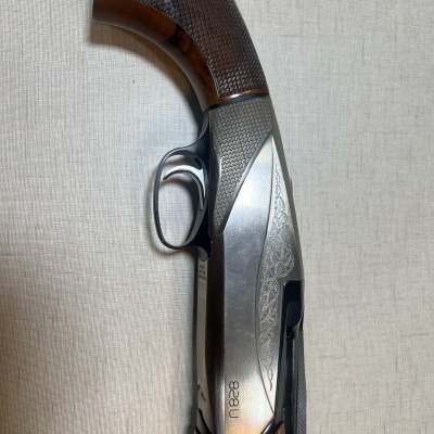 Espingarda de madeira e metal com detalhes gravados e número 18828 em fundo bege