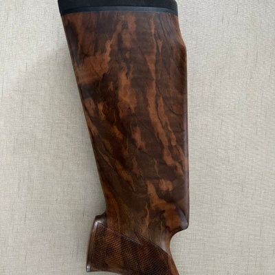 Cabo e parte superior de arma de fogo em madeira castanha com textura e detalhe preto