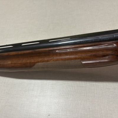 Espingarda Benelli com base em madeira e parte superior metálica preta num fundo claro