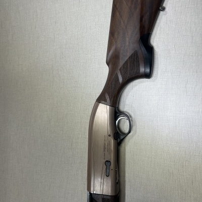 Espingarda com cano prateado e coronha de madeira escura em fundo claro