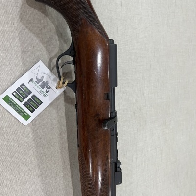 Carabina de madeira com etiqueta branca pendurada em fundo de tecido claro