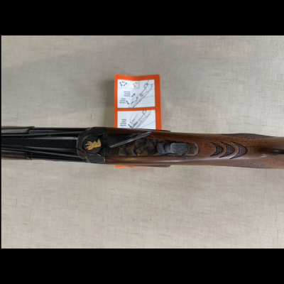 Espingarda canos duplos com coronha em madeira entalhada e manual laranja ao fundo