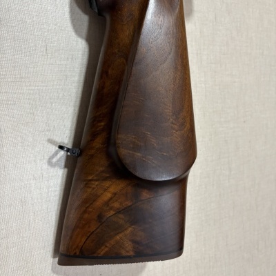 Coronha de madeira polida castanha com padrão natural e acabamento liso contra parede cinza.