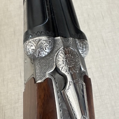 Espingarda dupla com madeira e metal gravado em fundo claro