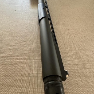 Espingarda de cano preto metálico sobre superfície bege texturizada