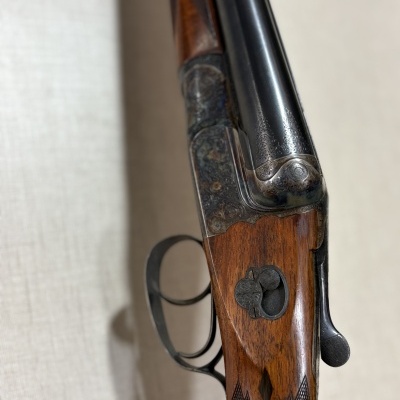 Espingarda de canos duplos com corpo em madeira e detalhes em metal gravado.