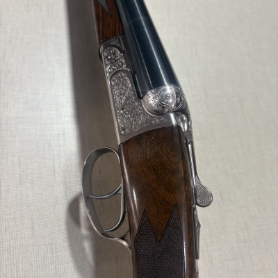 Espingarda de caça com coronha em madeira castanha e armação metálica prateada com gravações