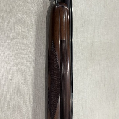 Coronha de madeira castanha com textura e tubo metálico preto em fundo de tecido claro