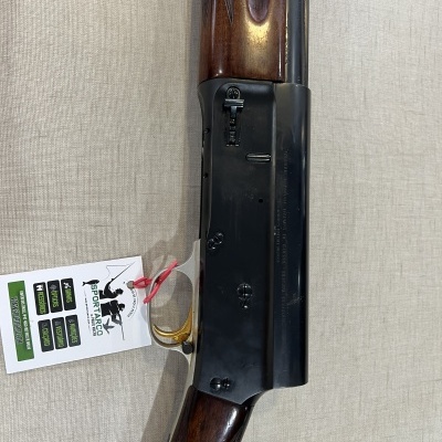 Espingarda de caça em madeira castanha e metal preto com etiqueta branca pendurada