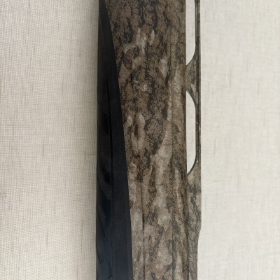 Parte da arma com padrão camuflado castanho e preto e grip preto emborrachado