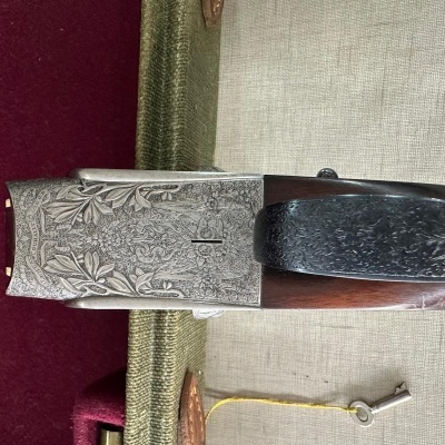 Espingarda com receptor em metal gravado e coronha de madeira sobre superfície de tecido