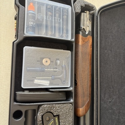 Arma Beretta com empunhadura de madeira e acessórios em mala preta com espuma.