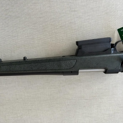 Espingarda preta com etiqueta verde numa superfície clara