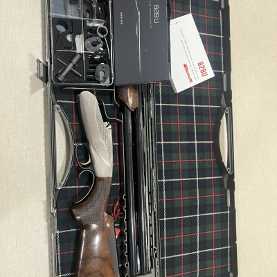 Estojo aberto com caçadeira desmontada, ferramentas e cartão '828U', fundo xadrez