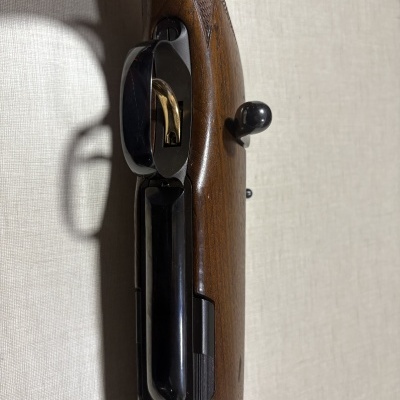 Espingarda com madeira castanha, gatilho dourado e detalhes metálicos pretos