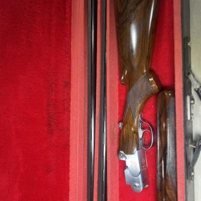 Espingarda desmontada em estojo vermelho com madeira castanha e metal prateado