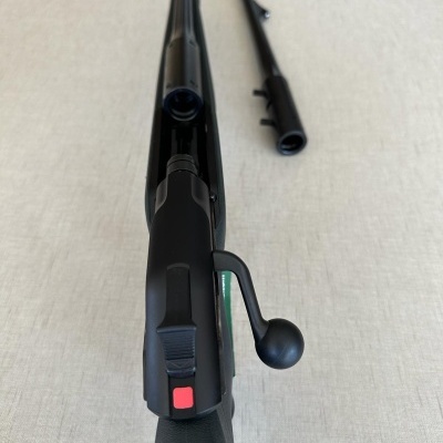 Espingarda ou carabina preta com mecanismo de ferrolho sobre tecido claro