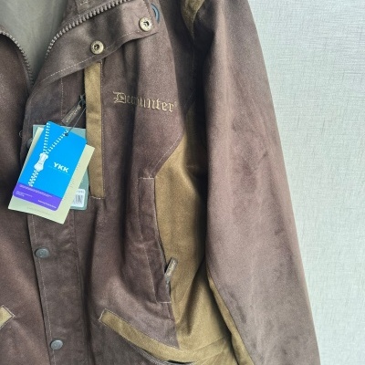 Casaco Deerhunter castanho com bolso frontal e etiquetas pendurado num cabide