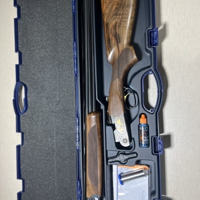 Estojo aberto com espingarda de cano duplo, óleo lubrificante e acessórios