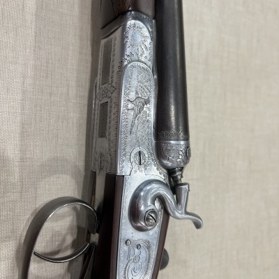 Espingarda com coronha em madeira escura e detalhes metálicos gravados