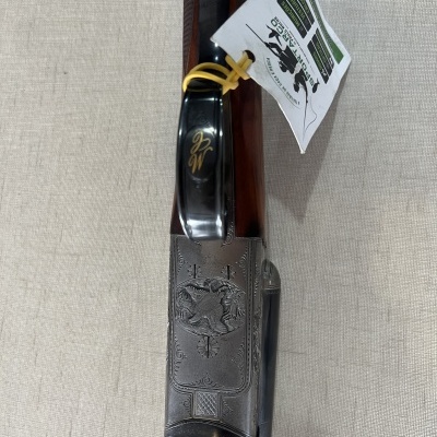 Arma de fogo com cabo em madeira e metal gravado, etiqueta branca com texto