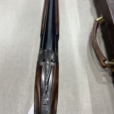 Espingarda de canos duplos em madeira e metal com detalhe em superfície clara