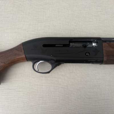 Espingarda Beretta Ultra Lite com madeira e metal preto numa superfície clara.