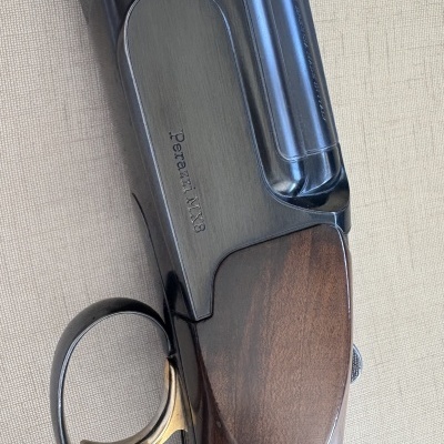 Rifle Perazzi MX8 com punho em madeira castanha e detalhe de gatilho dourado