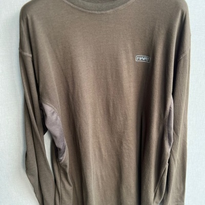 Camisola castanha de manga comprida com etiqueta HART, pendurada num cabide preto.