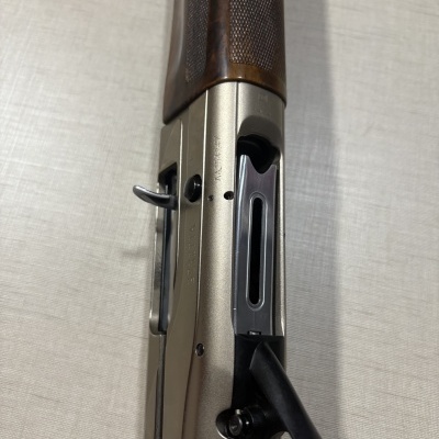 Espingarda com punho de madeira e corpo metálico prateado