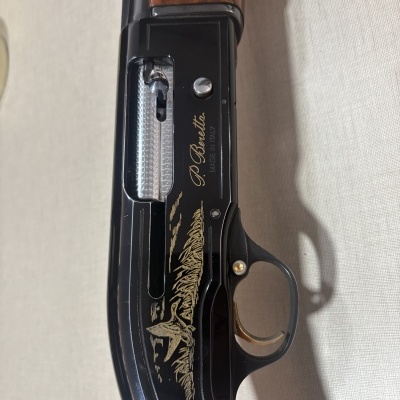Espingarda com madeira castanha e metal preto com gravura dourada e texto P. Beretta.