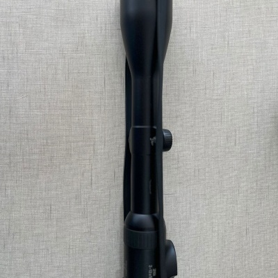 Mira telescópica preta sobre superfície cinza de tecido